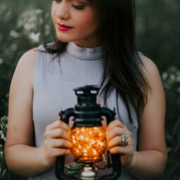 woman in gray turtle neckline top holding black camping lantern